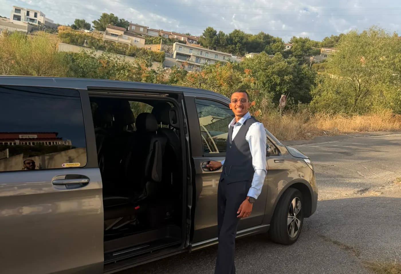 Chauffeur partenaire VTC Avenue accueillant un voyageur devant un van